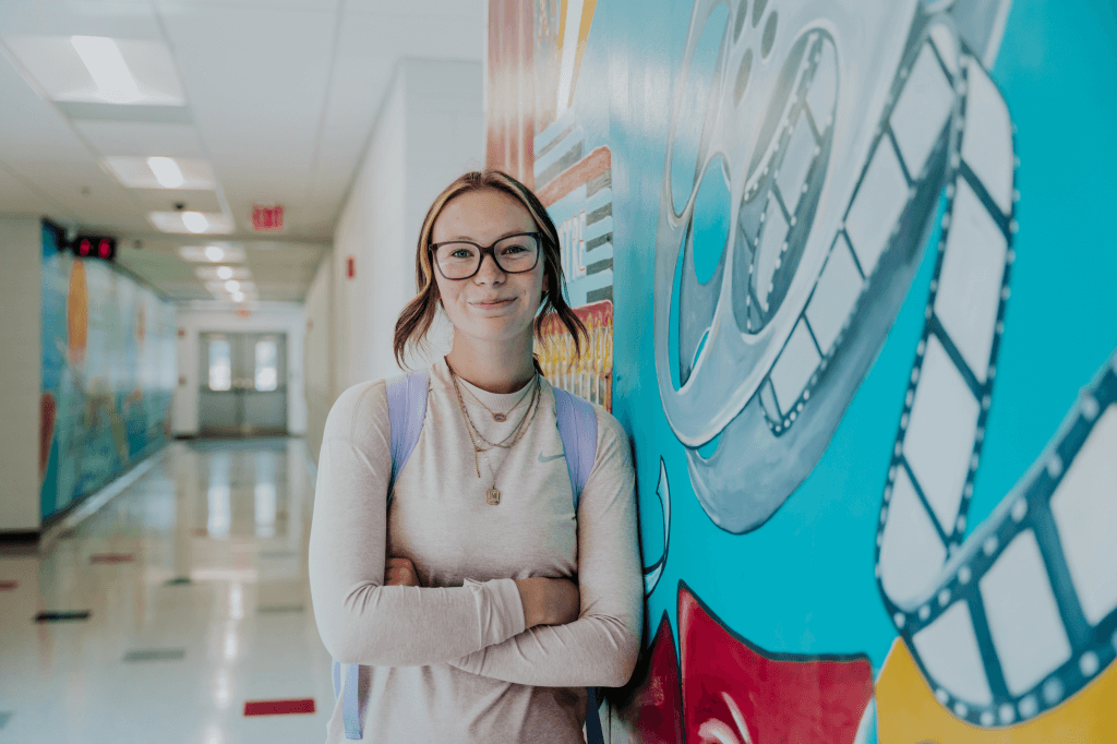 a girl standing in a hallway with her arms crossed